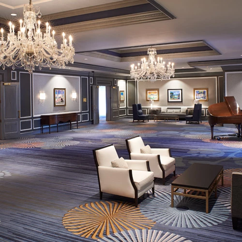 event area with seats and tables spread out two chandeliers hanging from the ceiling and a view of a piano