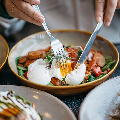 close up shot of a breakfast dish with an egg being cut into
