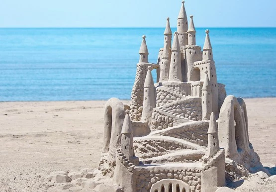 Big & detailed sand castle beside the ocean water