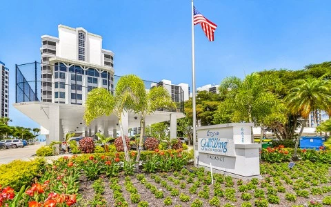 a flag pole with flowers and plants in front of a building