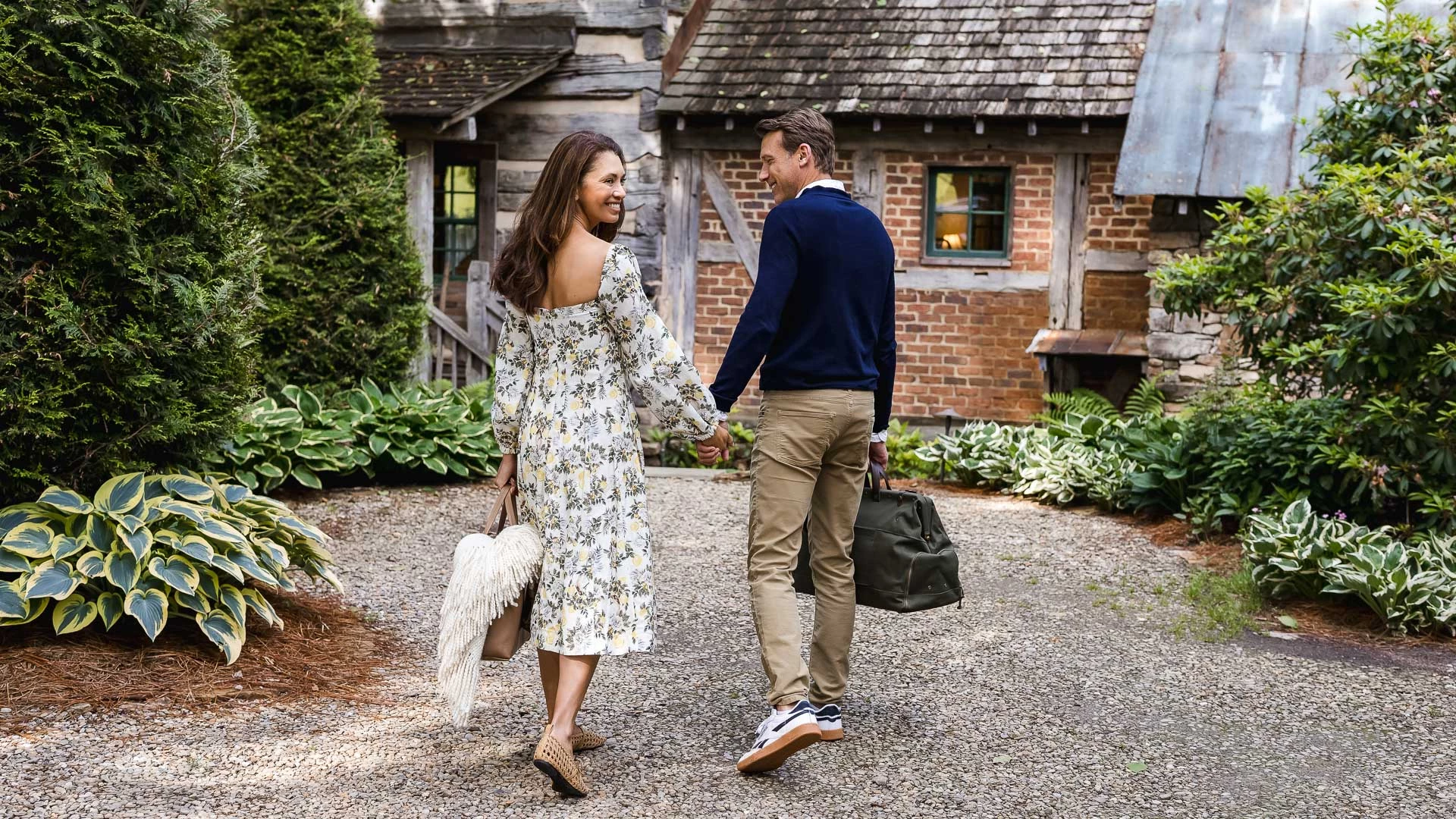 a man and woman holding hands and walking in front of a house