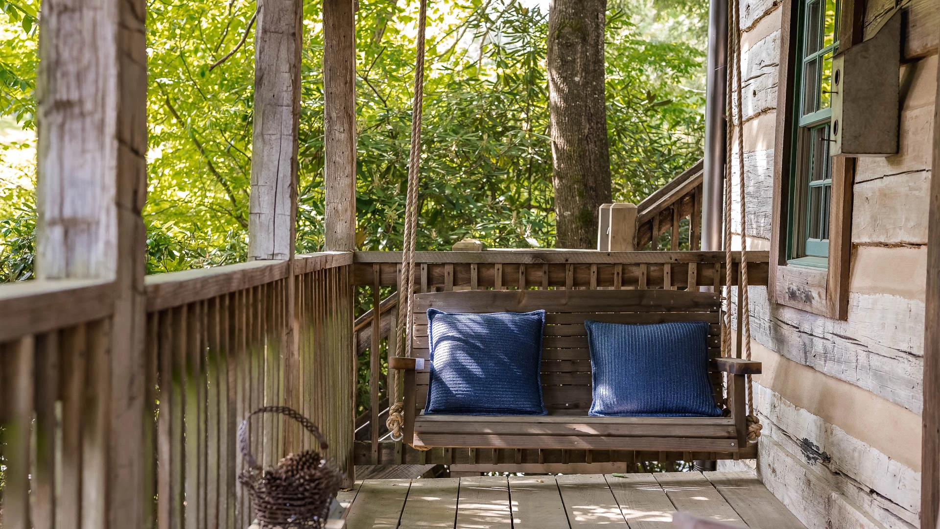 a wooden swing with pillows on a porch
