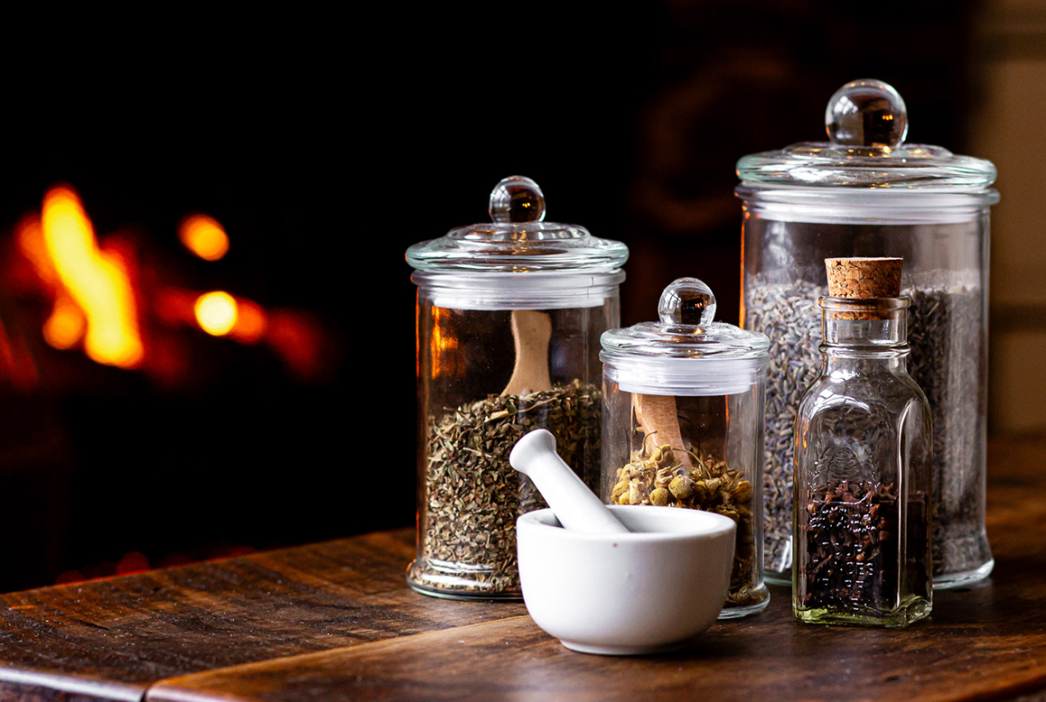 a group of glass jars with different spices and mortar