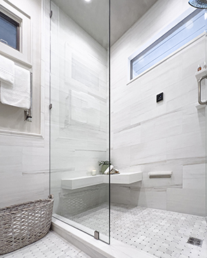 a glass shower with a bench and a basket