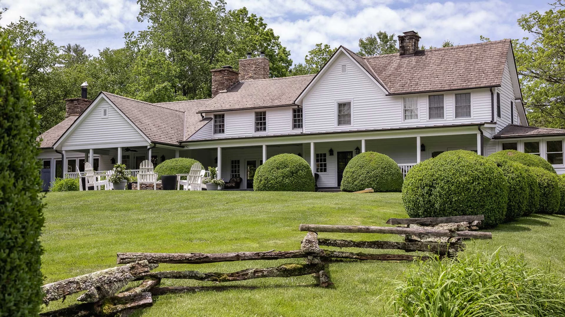 a large white house with a fence and bushes with Robert Frost Farm in the background