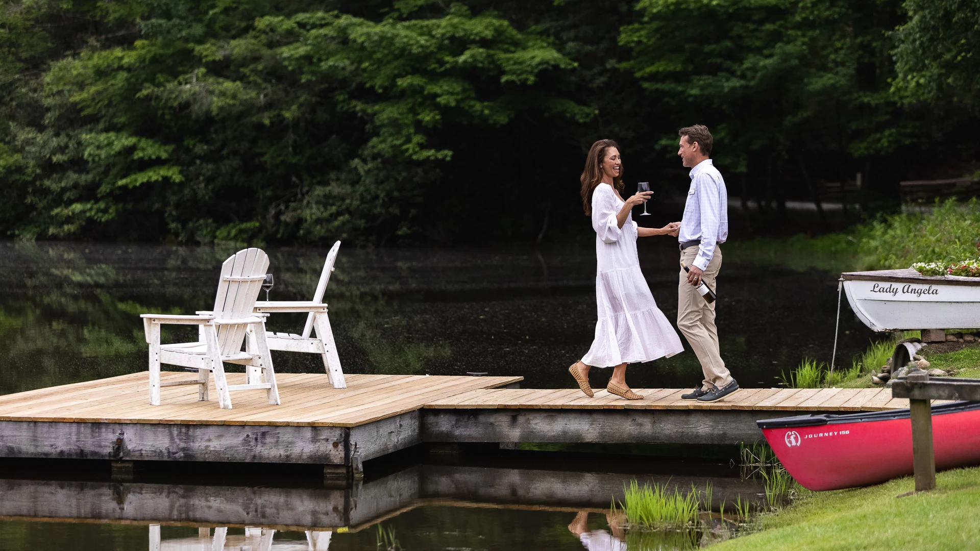 a man and woman on a dock with wine glasses