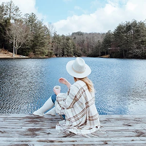 a woman sitting on a dock by a lake