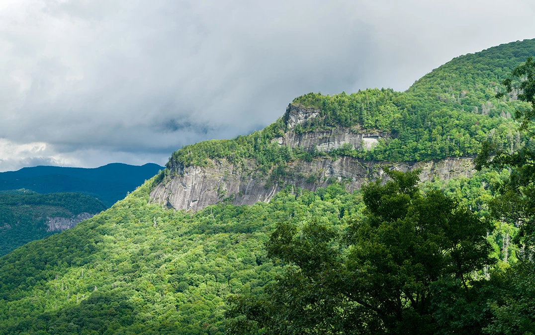 a mountain with trees and clouds