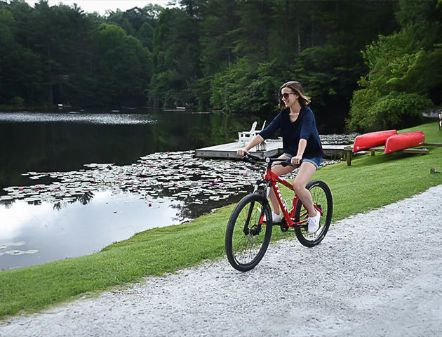 a woman riding a bike near a lake