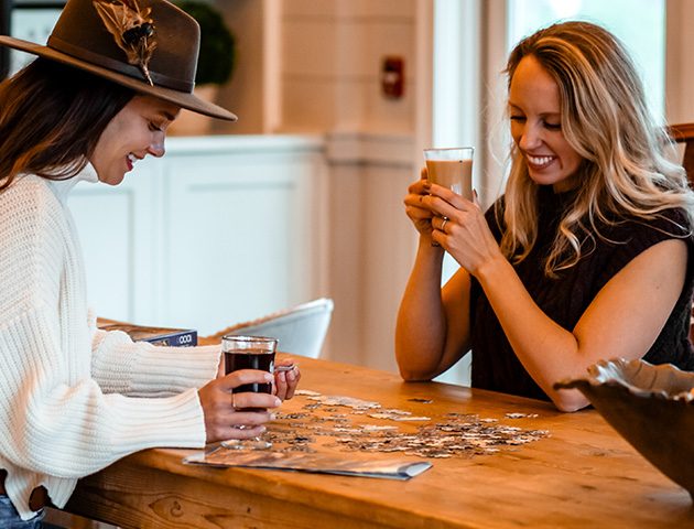 two women sitting at a table holding drinks