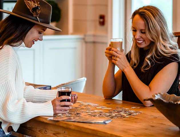 two women sitting at a table holding drinks