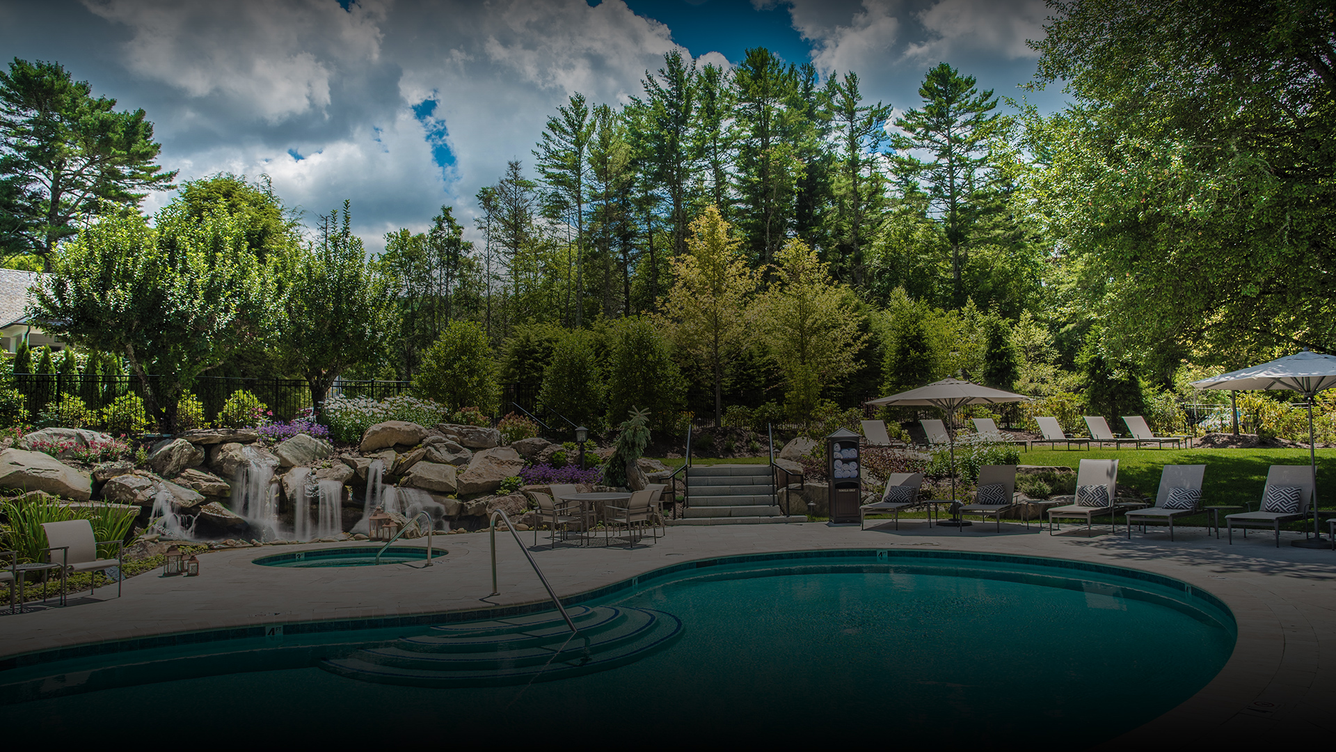 a pool with a waterfall and trees