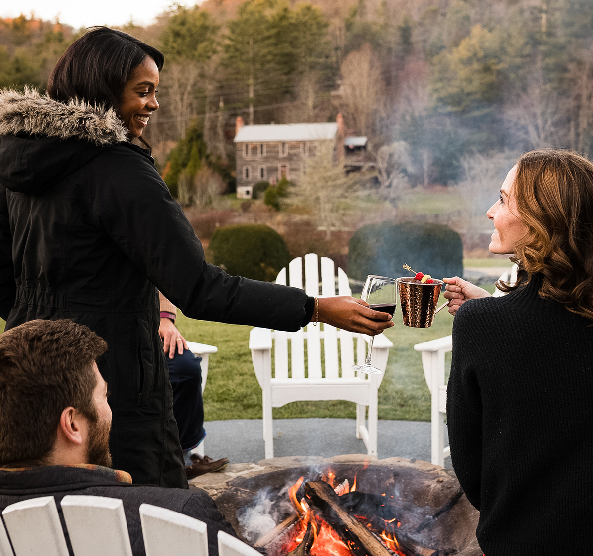 a group of people holding drinks in front of a fire pit