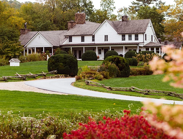 a large white house with a driveway and bushes