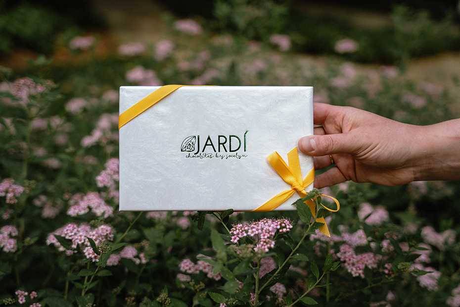 a hand holding a white rectangular object with a yellow ribbon