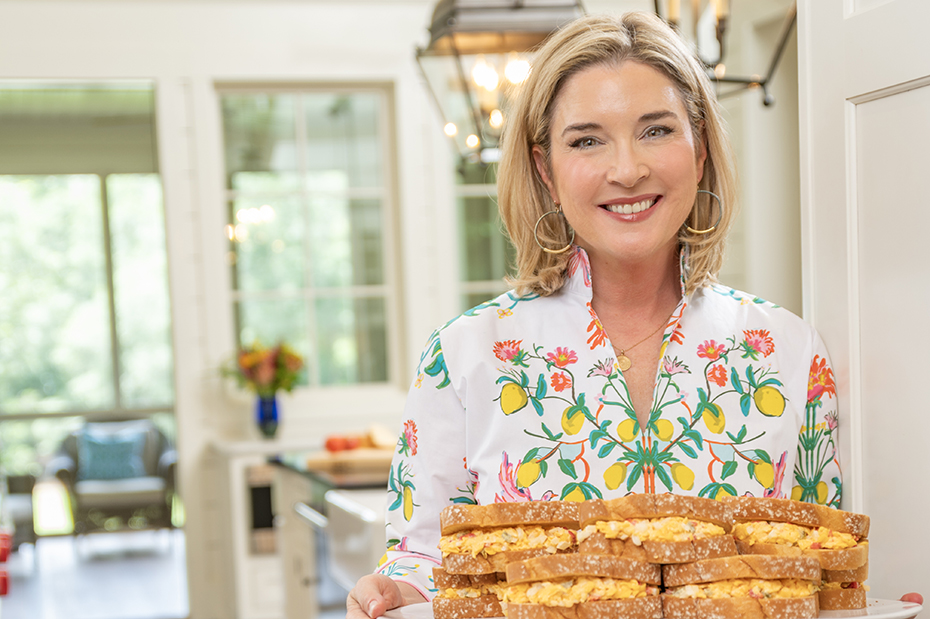 a woman holding a plate of sandwiches