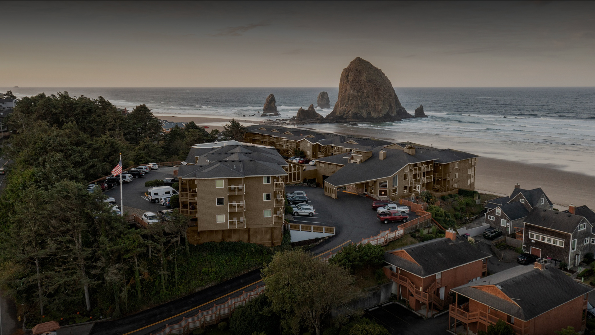 a group of buildings with cars parked on a beach