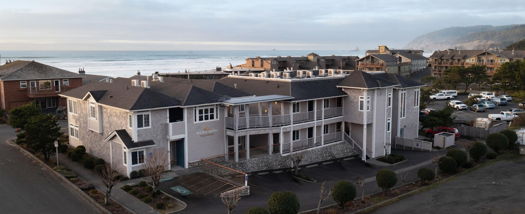 a building with a lot of windows and a parking lot with a body of water in the background