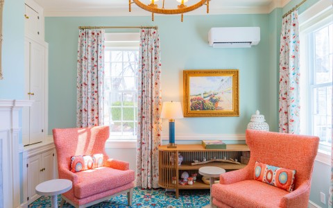 a living room with pink chairs and a table