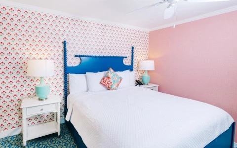 a bed with a blue headboard and a white lamp on a table