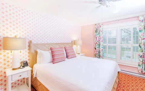 a bed with a white bed and pink wallpaper