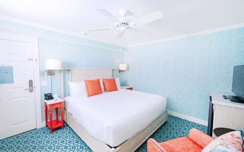 a bed with orange pillows and a white ceiling fan