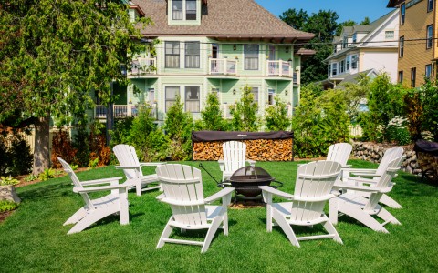 a lawn with chairs around a fire pit