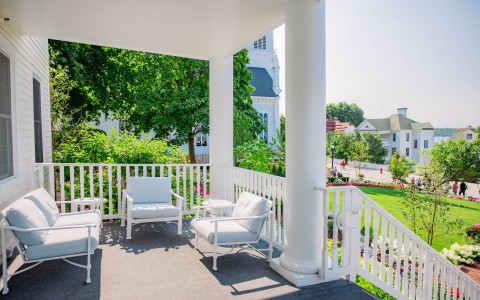 a white porch with white chairs and a white railing