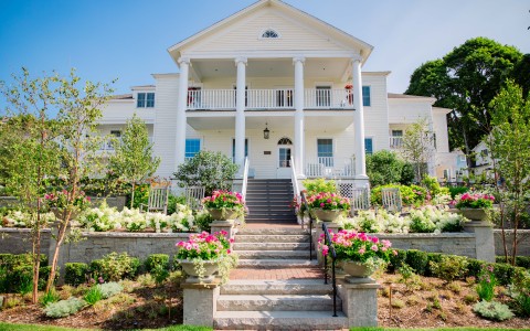 a white house with columns and a garden