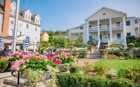 a large white house with many flowers in front of it