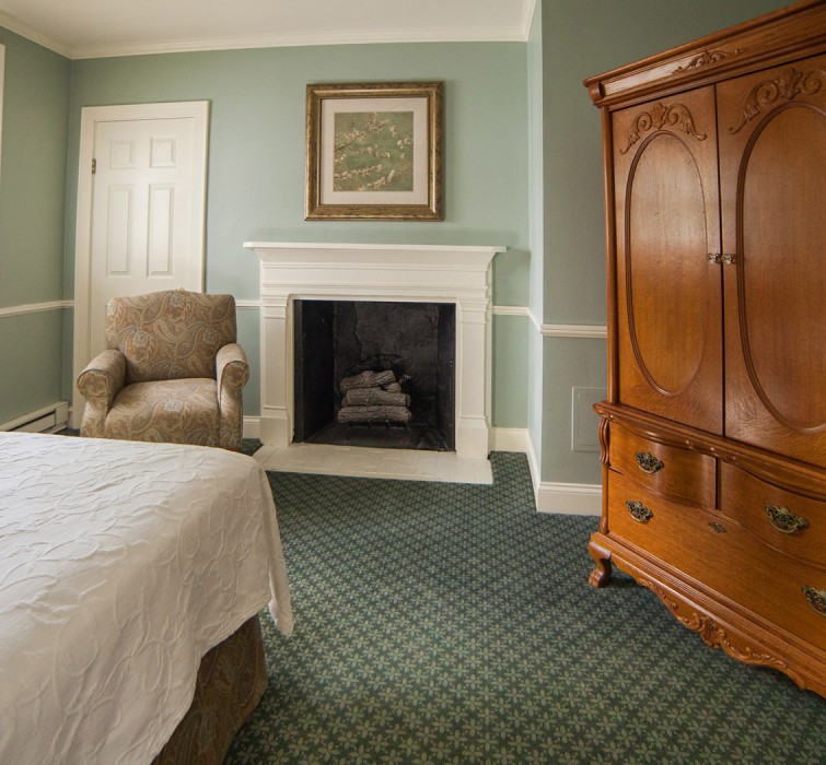 Internal view of a room with a fireplace, a wooden closet and a big bed
