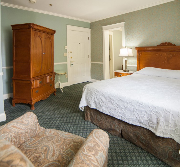 View of a big room with a wooden bed, a closet and an armchair