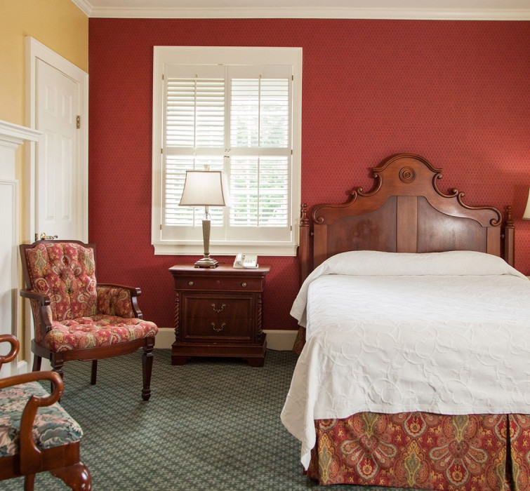 Internal view of a room with a big comfortable bed, a private fireplace and some armchairs