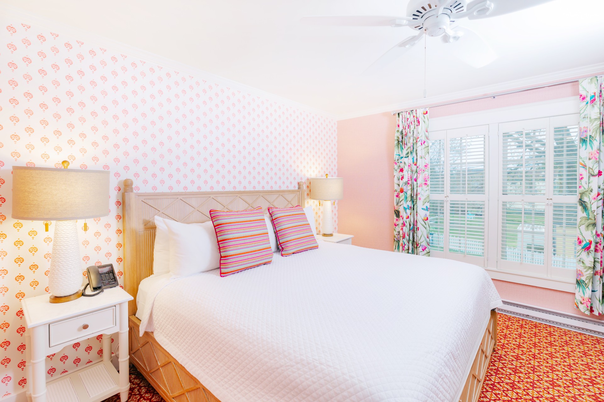 a bed with a white bed and pink wallpaper