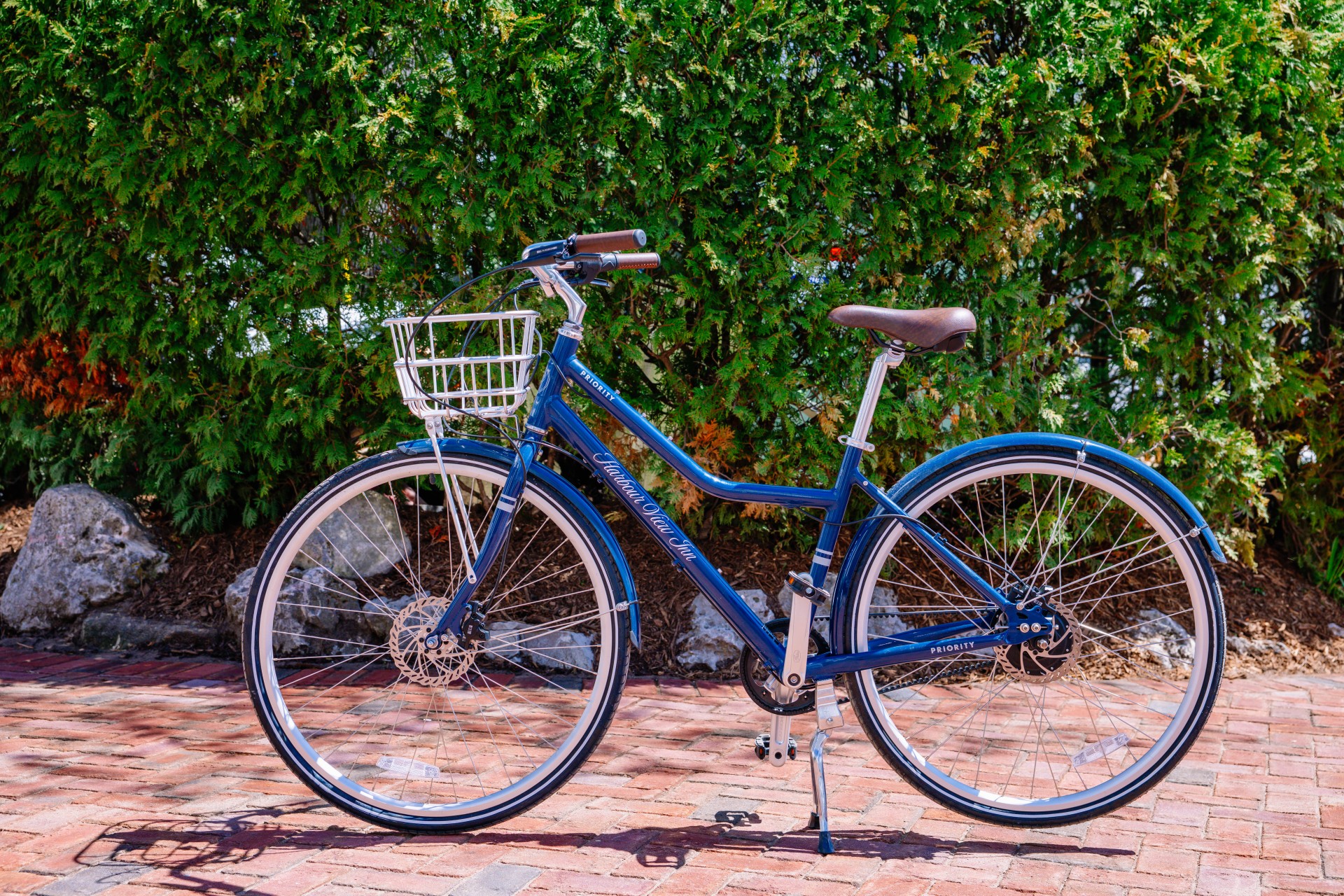 a blue bicycle with a basket on a brick sidewalk