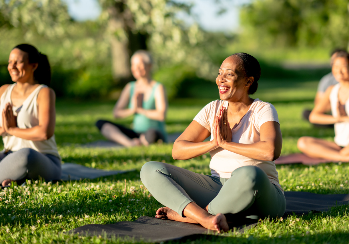 a group of people sitting on yoga mats in the grass