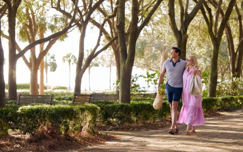 a man and woman walking down a path with trees