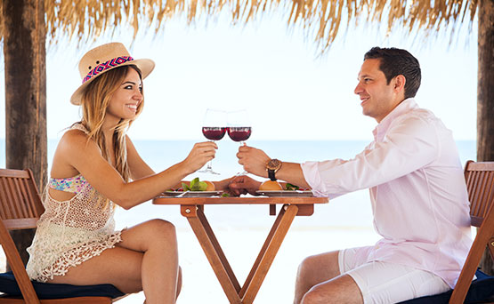 view of couple toasting while dining oceanside