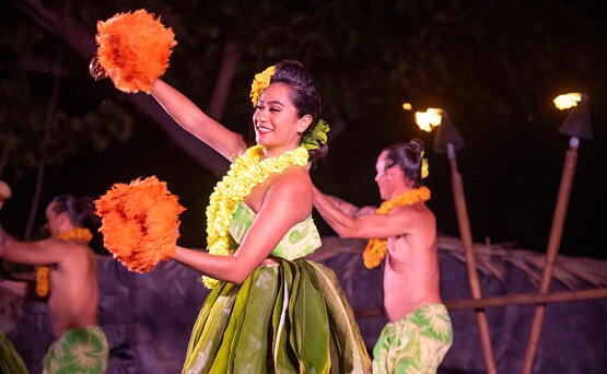woman with orange maracas participating in luau performance 