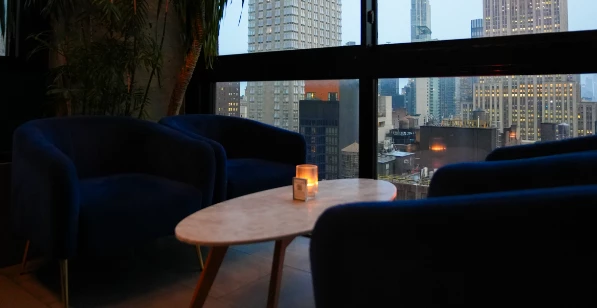 a table with a candle in it by a window with a city view