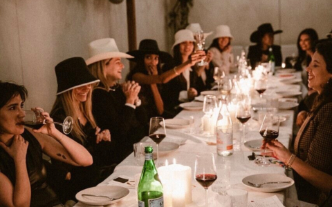 a group of women sitting at a long table with wine glasses and candles