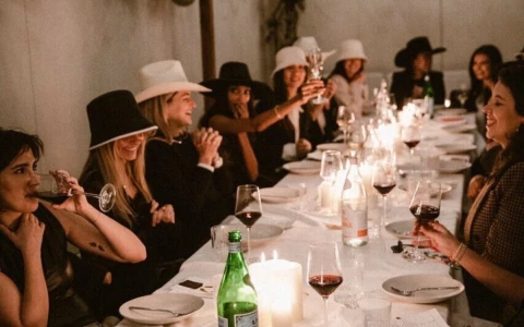 a group of women sitting at a long table with wine glasses and candles