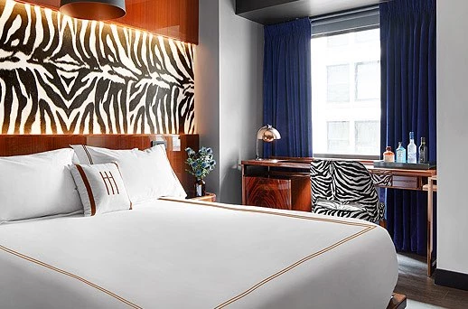 A hotel room with a large bed, desk, and window