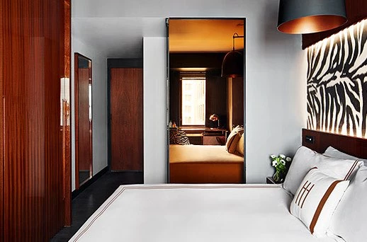 A modern hotel room with a large bed, wood paneling, and a zebra-print artwork above the bed.