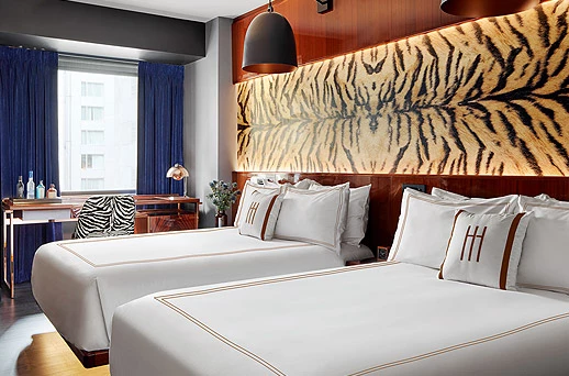 A hotel room with two twin beds, a desk, and a large window.