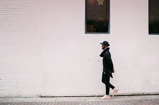 a man walking down a side street in front of a white building