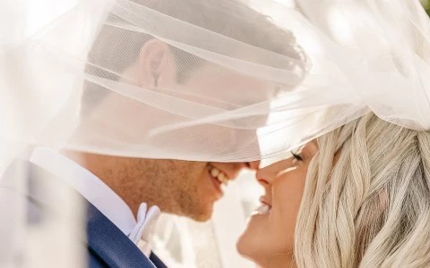 Closeup up of newly wedded couple embracing for a kiss.