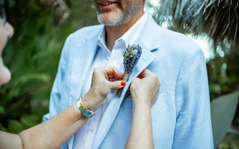 a person tying a flower on a man's jacket