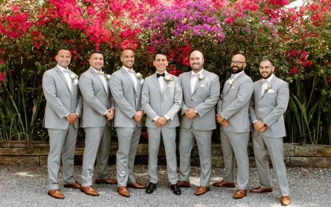 a group of men in suits standing in front of a flowering tree