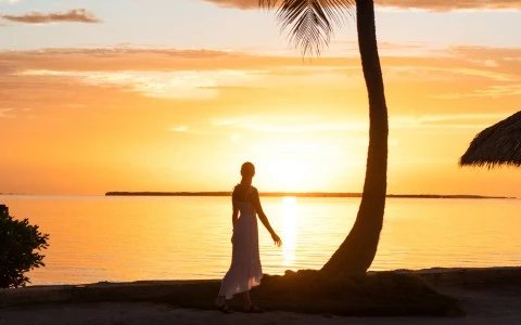 Bride posing for a photo while overlooking the ocean during a sunset.